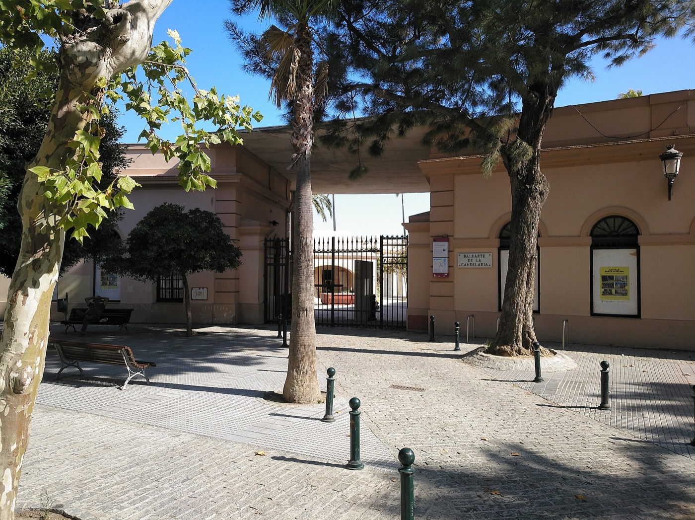 La entrada del Baluarte de la Candelaria de Cádiz, con su rótulo, entre palmeras y pinos