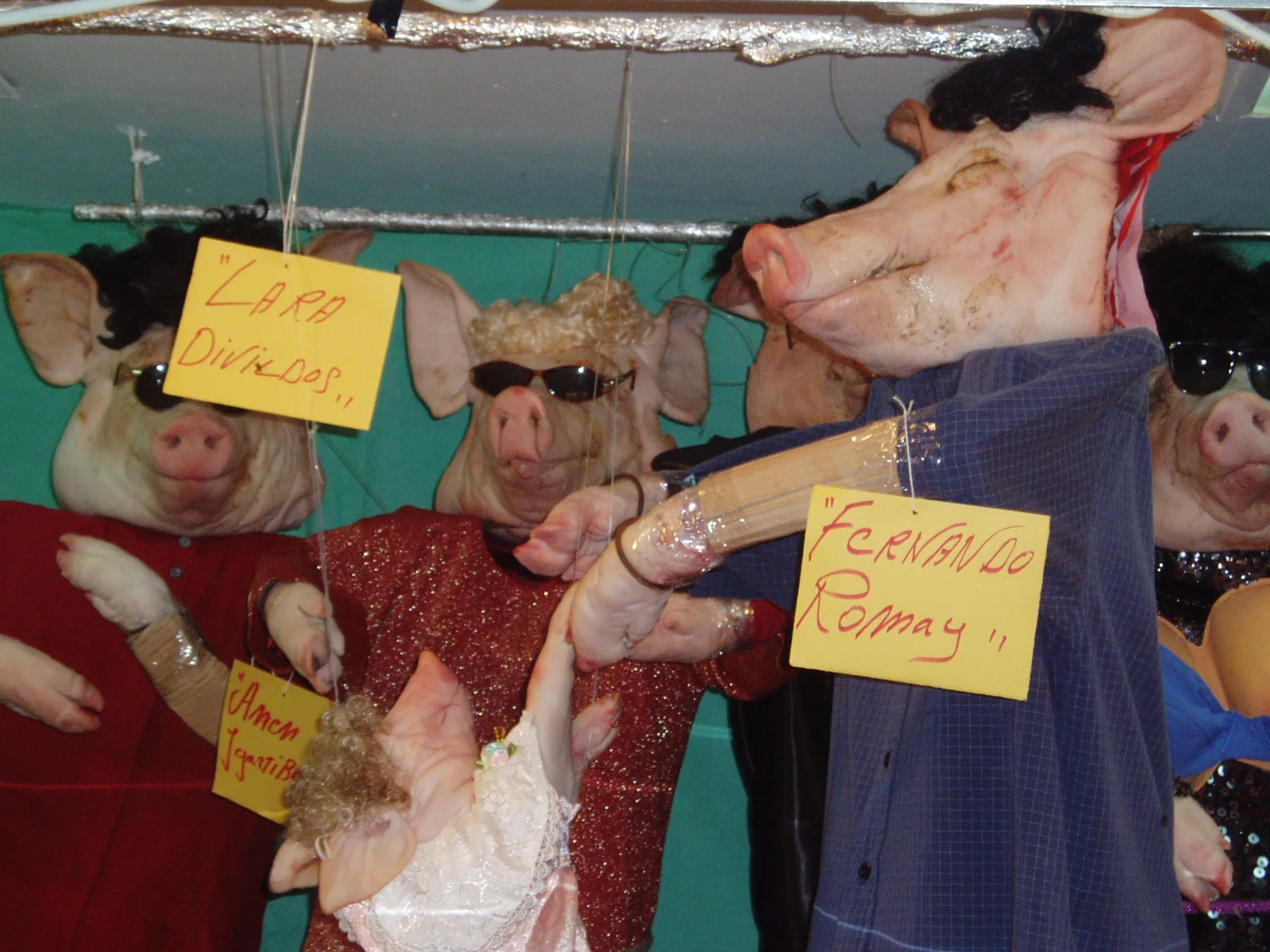 Puesto exornado por Tosantos en un mercado de Cádiz: cabezas de cerdo con pelucas, gafas de sol y ropa, con carteles de humor que satirizan a personajes conocidos