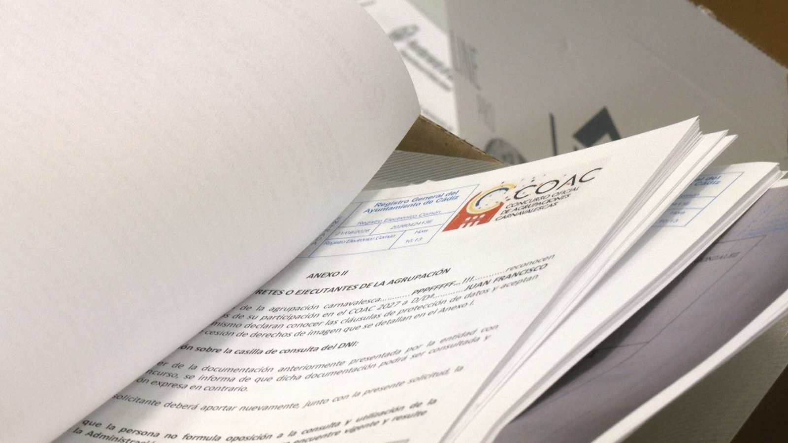 Documentos del COAC con el anexo II de datos de una agrupación, sobre una caja de cartón.