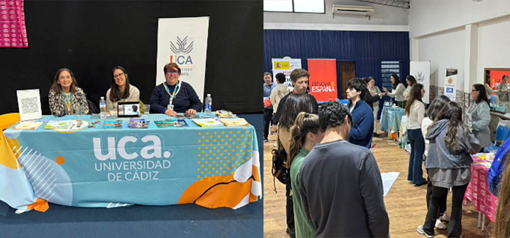 Puesto informativo con mantel azul de la Universidad de Cádiz atendido por tres personas, junto a un recinto con asistentes y carteles.